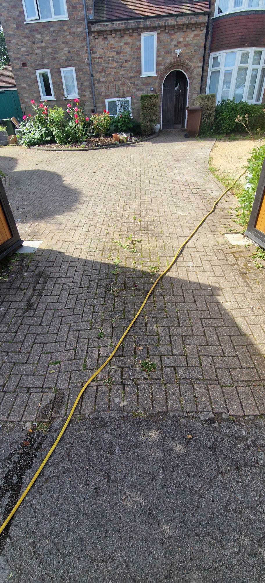 Dull, weed-flecked block paved driveway before pressure washing