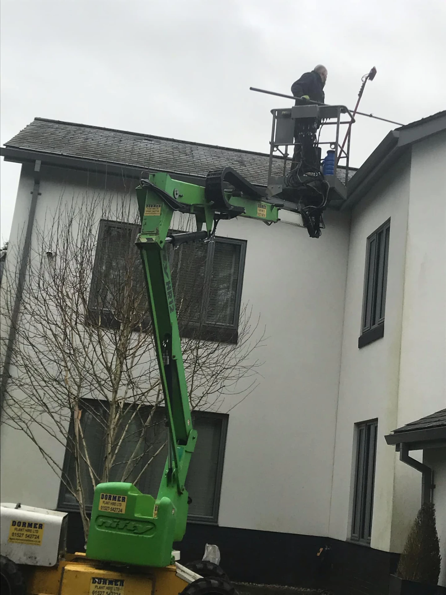 Roof cleaning from a cherry picker platform on a rendered detached house in Redditch, Worcestershire