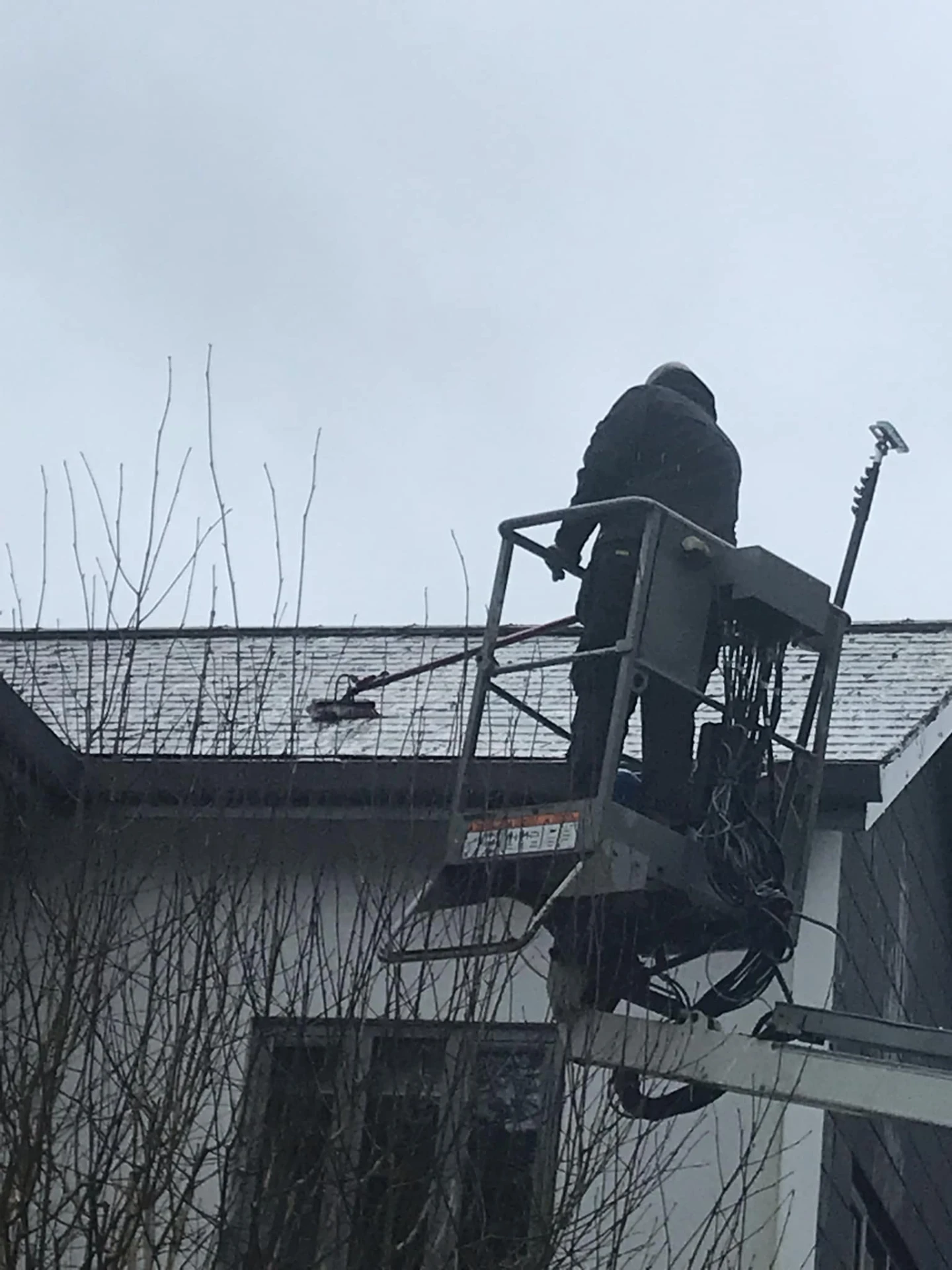Roof brushing from a cherry picker platform during roof cleaning in Redditch, Worcestershire