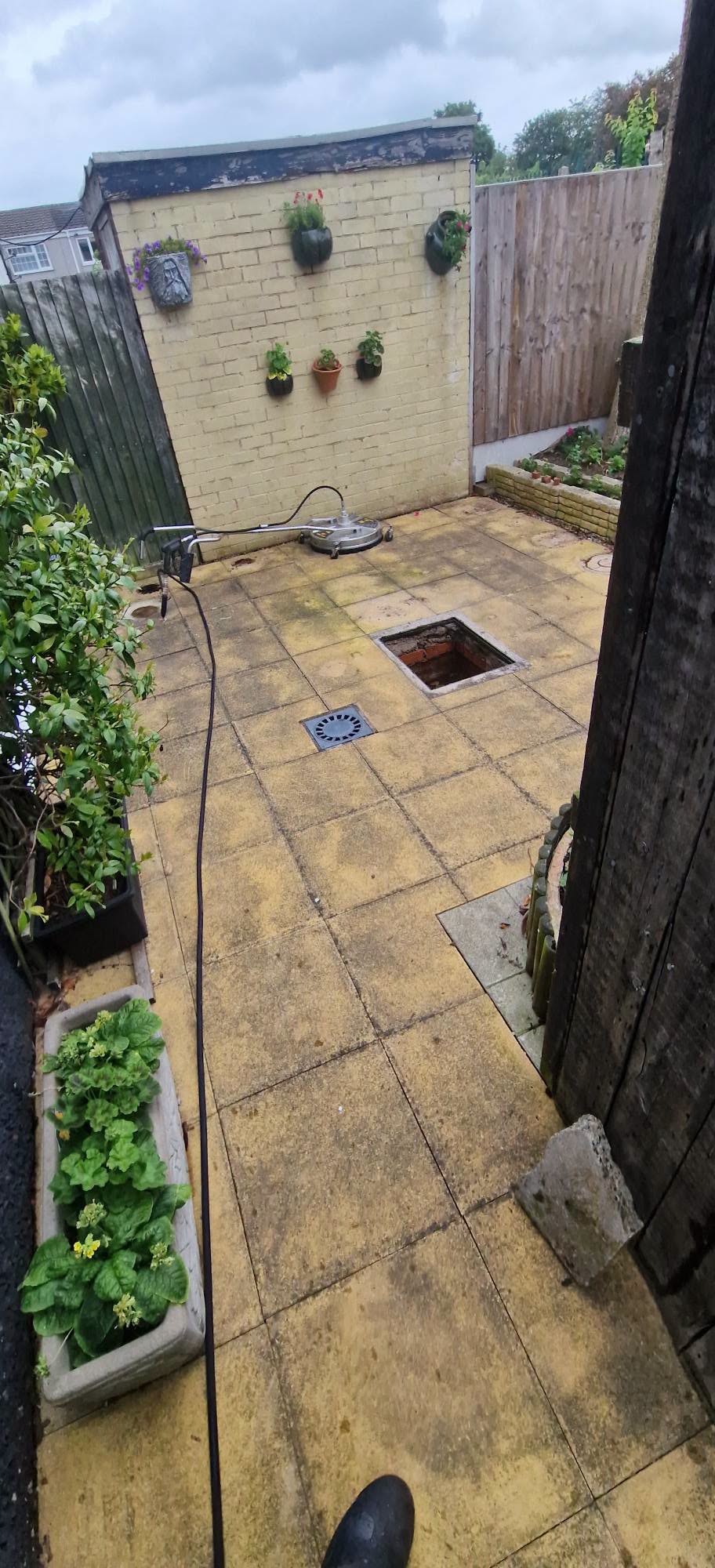 Algae-stained concrete courtyard patio slabs before pressure washing in Redditch