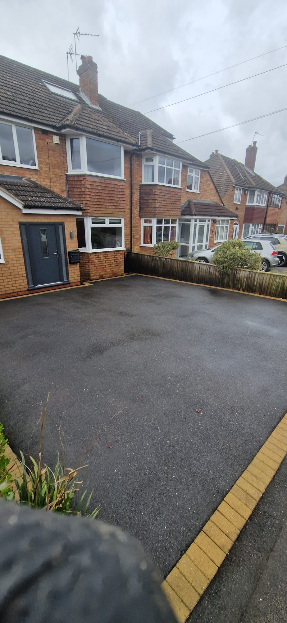 The same tarmac driveway cleaned to an even dark finish with crisp block paved edging