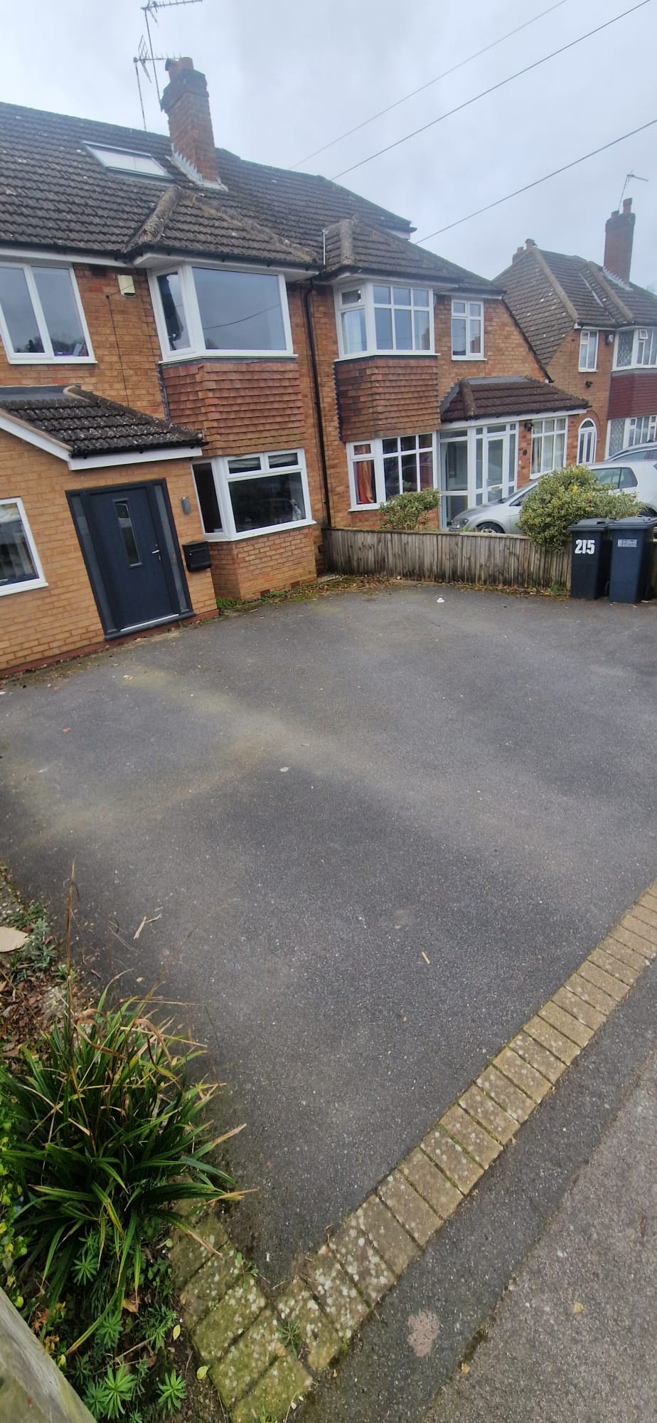 Front tarmac driveway with green algae staining and moss before pressure washing in Redditch