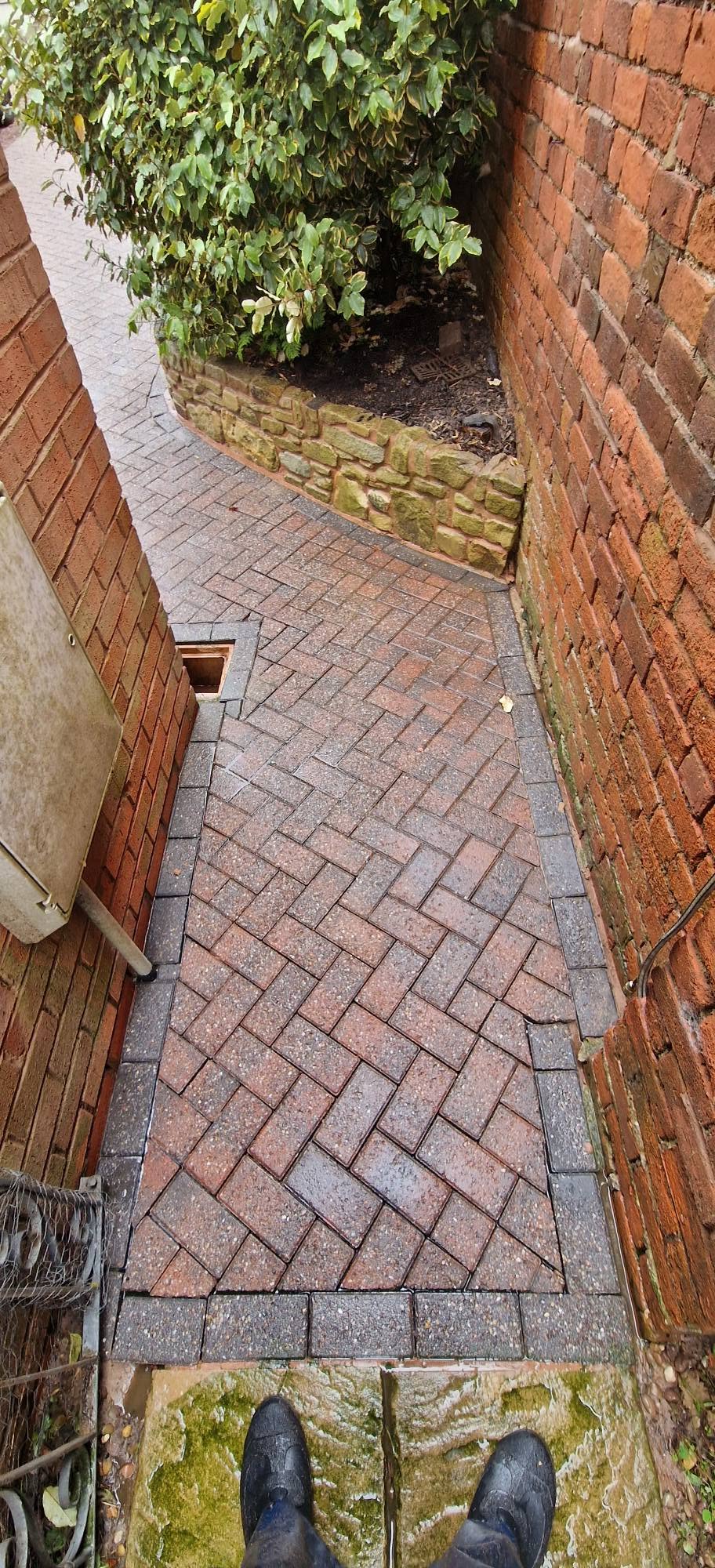 The same herringbone side path cleaned back to crisp red and charcoal block paving