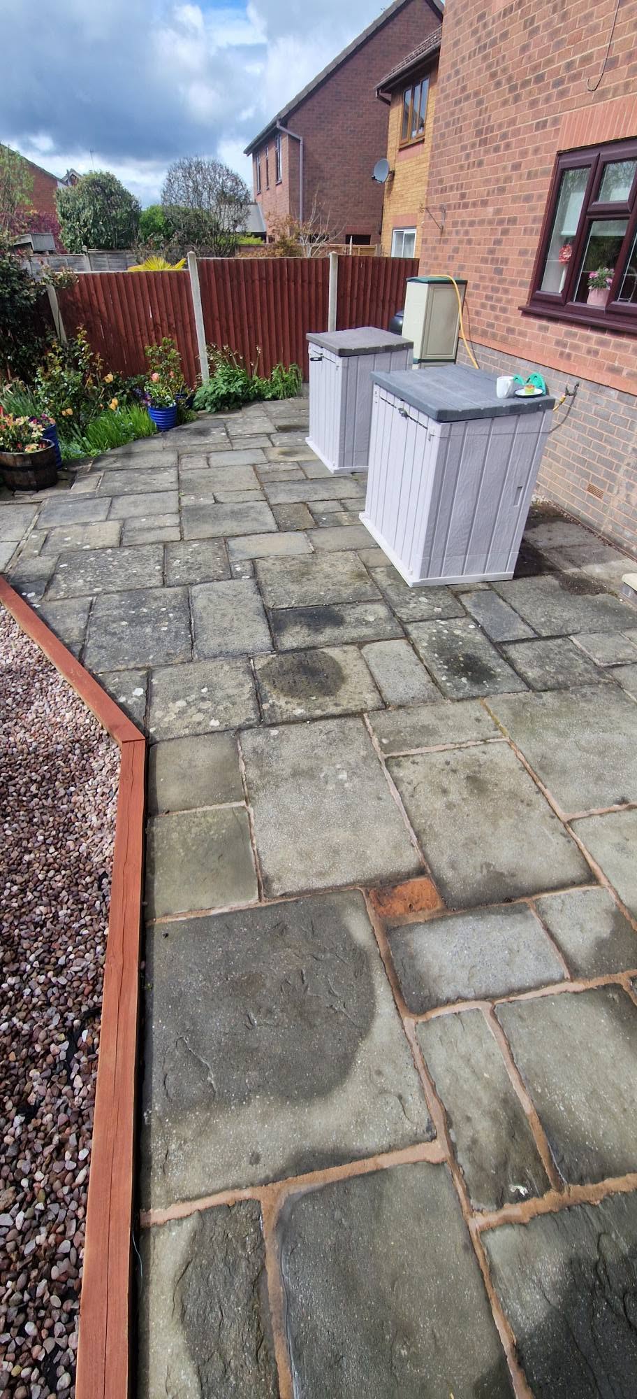 Grey riven flagstone patio dulled with dirt and algae before pressure washing
